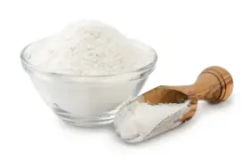 Una ciotola di vetro piena di polvere bianca, probabilmente aluminum starch octenylsuccinate, e un cucchiaio di legno con la stessa polvere.