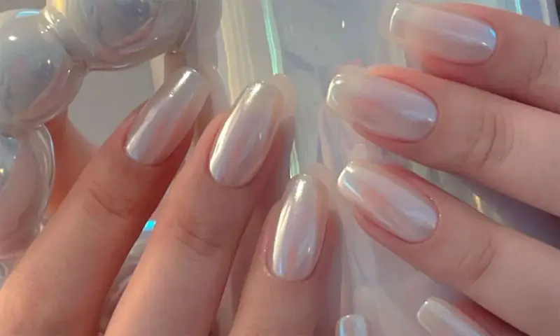 Mani eleganti con unghie a specchio perlate, che riflettono la luce con un effetto iridescente e sofisticato.