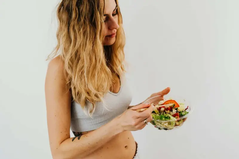 Donna con capelli biondi mangia un'insalata fresca, parte della sua vlckd dieta.